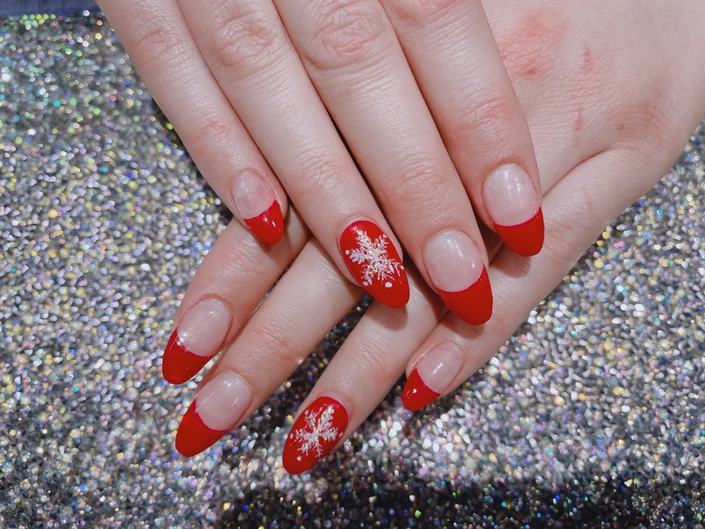 Red French-tip gel manicure with snowflake accent at Pleasant Nails & Spa